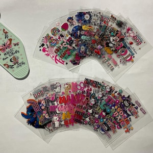 May include: A set of clear plastic sheets with colorful stickers featuring various designs and phrases, including "Magic Moon Butterfly", "Be Kind", "Feelin' Good", "Social Anxiety", and "Mom My All Time Favorite".