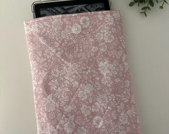 May include: A pink floral patterned fabric case with a white button closure for an e-reader.