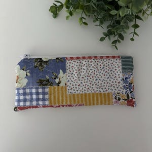 May include: A patchwork fabric zippered pouch with a variety of floral and geometric patterns in shades of blue, yellow, red, and white.