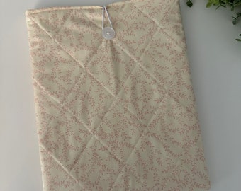 May include: A cream-colored quilted fabric pouch with a pink floral pattern and a white button closure.