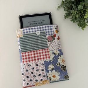 Peut inclure: Une housse pour liseuse en tissu patchwork matelassé avec un motif floral. La housse a une fermeture à bouton et est conçue pour s'adapter à une liseuse Kindle. Le texte sur l'écran de la liseuse indique "Discover books that read Great on Kindle. Great reading experience at a better value."