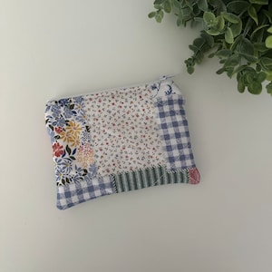 May include: A small patchwork zippered pouch with a blue and white gingham pattern, a floral pattern, and a green and white striped pattern.