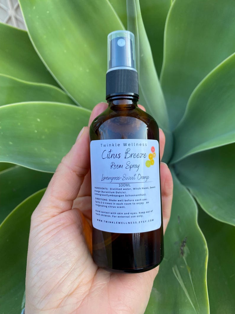 May include: A brown glass bottle with a black spray nozzle. The bottle is labeled "Twinkle Wellness Citrus Breeze Room Spray Lemongrass-Sweet Orange 100ML". The label also includes ingredients and directions for use.