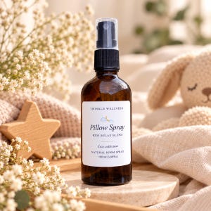 May include: A brown glass spray bottle with a black pump top and a white label. The label reads TWINKLE WELLNESS, Pillow Spray, KIDS RELAX BLEND, Cozy collection, NATURAL ROOM SPRAY, 100 ml | 3.38 fl oz, with a small moon and cloud icon.