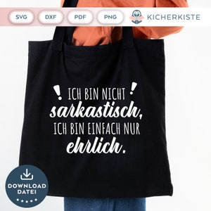 May include: A black tote bag with white text that reads "! ICH BIN NICHT! sarkastisch, ICH BIN EINFACH NUR ehrlich."