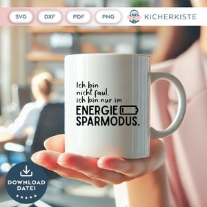 May include: White coffee mug with black text that reads "Ich bin nicht faul. Ich bin nur im ENERGIE SPARMODUS."  The mug is held in a person's hand.