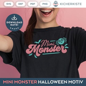 May include: A black t-shirt with a pink and teal graphic that says "Mini Monster" with a cartoon spider above the text. The shirt is being worn by a person with a pink background.