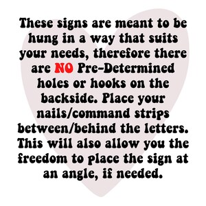 May include: A heart-shaped sign with the text "These signs are meant to be hung in a way that suits your needs, therefore there are NO Pre-Determined holes or hooks on the backside. Place your nails/command strips between/behind the letters. This will also allow you the freedom to place the sign at an angle, if needed."