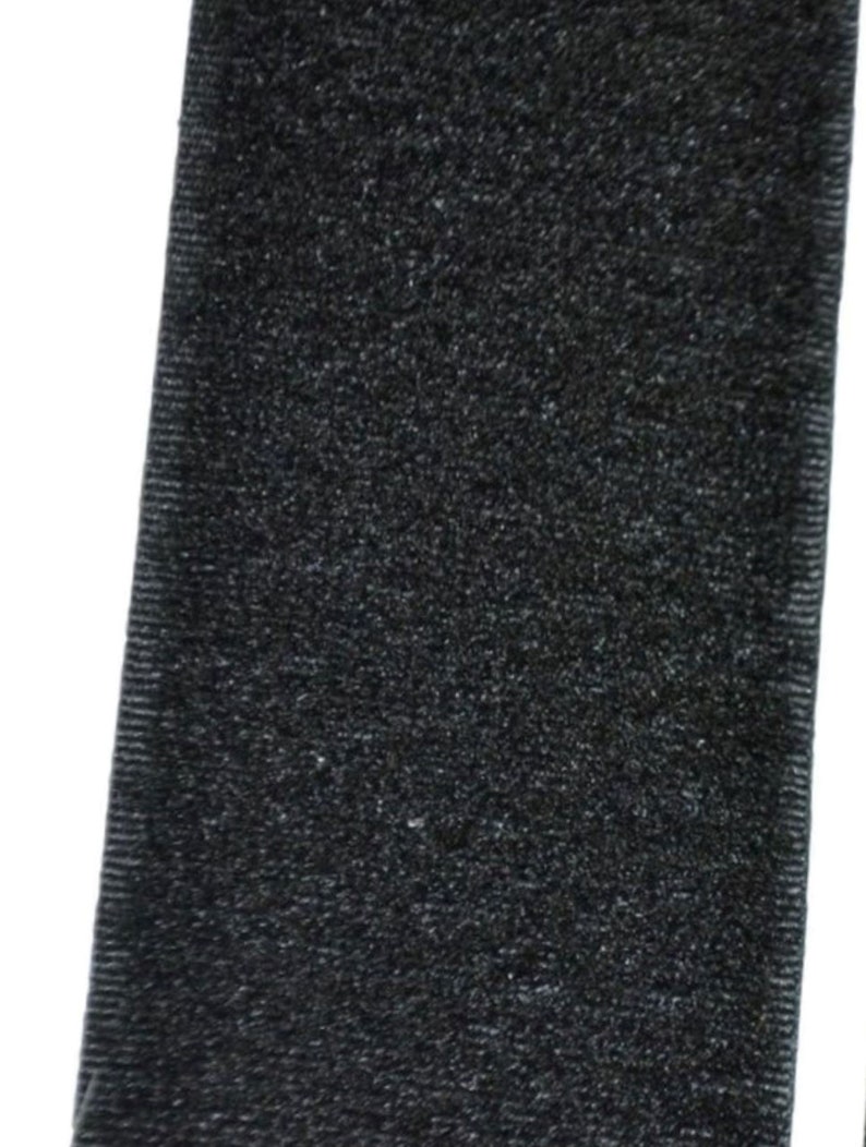 Op de afbeelding: Zwarte klittenband, ook wel bekend als Velcro, met een zachte, pluche textuur.