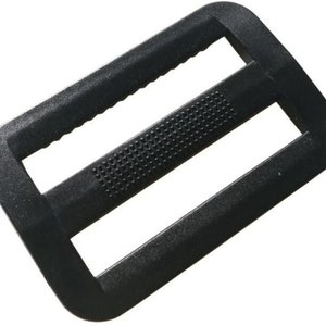 May include: Black plastic slider buckle with a textured surface. The buckle has two slots for webbing.