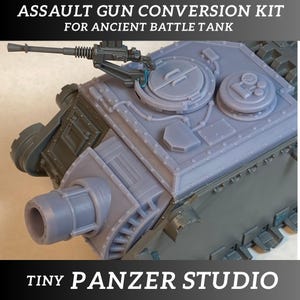 Può includere: Un kit di conversione per carri armati in plastica grigia. Il kit include un cannone di grosso calibro, un cannone di piccolo calibro e uno sportellino. Il kit è etichettato "Assault Gun Conversion Kit for Ancient Battle Tank" e "Tiny Panzer Studio".