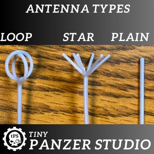 May include: Three different types of antennas for model making: a loop antenna, a star antenna, and a plain antenna. The antennas are white and made of plastic. The antennas are on a wooden surface.