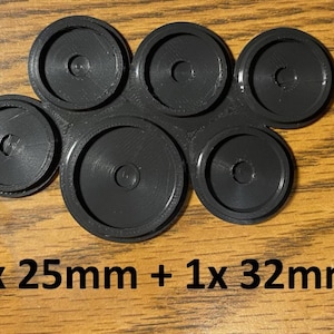 May include: A black plastic component with six circular parts. Five are 25mm in diameter, and one is 32mm. The parts are arranged in a cluster, with a central hole in each. The text "5x 25mm + 1x 32mm" is at the bottom.