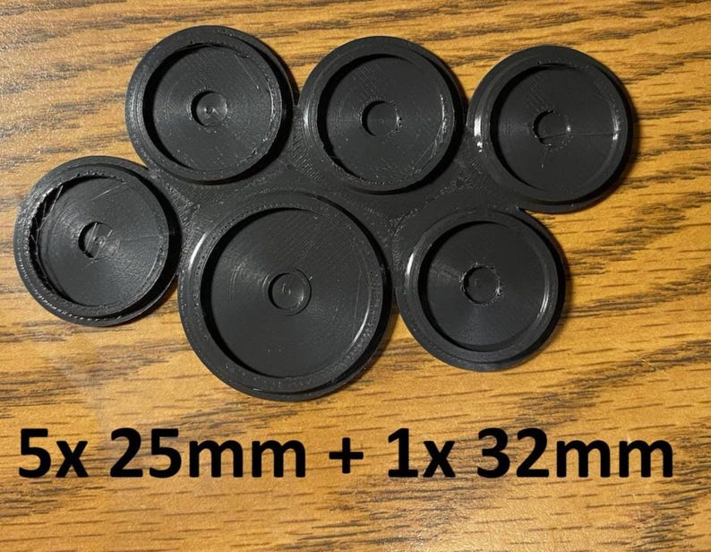 May include: A black plastic component with six circular parts. Five are 25mm in diameter, and one is 32mm. The parts are arranged in a cluster, with a central hole in each. The text "5x 25mm + 1x 32mm" is at the bottom.