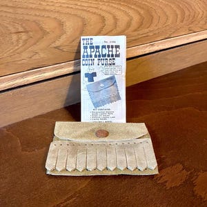 May include: A craft kit for making a leather coin purse. The kit includes pre-punched genuine suede leather parts, snaps, leather lace, and a lacing needle. The kit is labeled "The Apache Coin Purse" and has the number 4186.