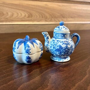 May include: A blue and white porcelain teapot and a pumpkin-shaped container with a lid. Both are decorated with floral patterns.