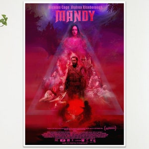 May include: A framed film poster for "Mandy" starring Nicolas Cage and Andrea Riseborough. The poster is predominantly red and purple, with the film's title at the top. The image features a central figure surrounded by other characters.