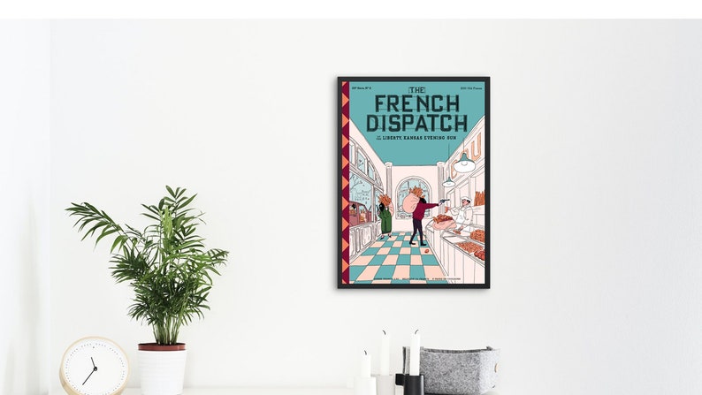 May include: Framed poster of "The French Dispatch" movie. The poster features a teal background with the title in white and a scene from the film. The scene depicts a shop interior with characters and text. The frame is black.