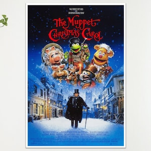 May include: A framed poster for "The Muppet Christmas Carol" film. The poster shows various Muppet characters in a snowy scene, with the title in red script. A man in a black coat walks in the foreground.