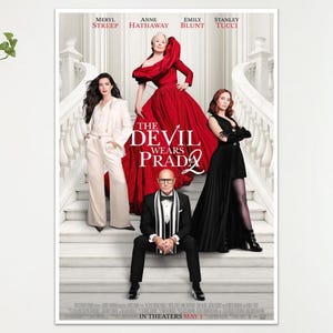 May include: A film poster for "The Devil Wears Prada 2" featuring Meryl Streep, Anne Hathaway, Emily Blunt, and Stanley Tucci. The poster shows the cast on a grand staircase. The title is in large, bold letters.