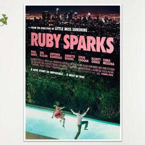 May include: A film poster for "Ruby Sparks" featuring a night cityscape. The title is in pink, with the cast names and the tagline "A love story so impossible... it must be true". Two figures are in a swimming pool.