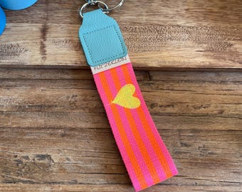 Colorful key fob made of pink and orange webbing, a yellow heart and light blue leather end, carabiner + key ring