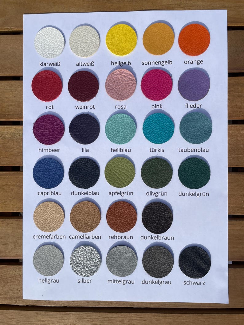 May include: A color chart featuring thirty circular leather swatches arranged in six rows and five columns. Each swatch displays a unique color, including white, yellow, orange, red, pink, purple, blue, green, brown, gray, and black, with text labels.