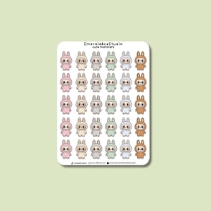 May include: A sticker sheet featuring multiple cartoon monster characters in various colors, including pink, gray, green, and brown. The stickers have a bunny-like appearance with large eyes and are wearing matching outfits. The text "EmeraldAceStudio cute monsters" is at the top.