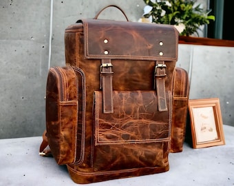 May include: A brown leather backpack with multiple pockets and buckles. The backpack has a distressed look and is made of high-quality leather.
