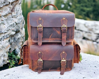 May include: A brown leather backpack with multiple pockets and buckles. The backpack has a distressed look and is made of high-quality leather.