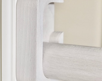 Könnte beinhalten: Eine weiße Gardinenstangenhalterung aus Holz mit C-förmigem Design, die über eine glatte, matte Oberfläche verfügt und eine zylindrische Stange sicher im geschwungenen Stützarm hält, wobei die natürliche Holzmaserung auf der Oberfläche sichtbar ist.