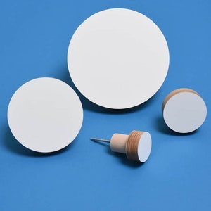 Könnte beinhalten: Drei weiße, runde Wandhaken aus Holz, zwei sind groß und einer ist ein kleiner runder Haken mit einem Holzsockel und einer Schraube. Die Haken befinden sich auf einem blauen Hintergrund.