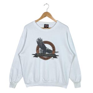May include: White long-sleeve sweatshirt with a Harley-Davidson Motorcycles logo featuring an eagle in flight and the text "Harley-Davidson Since 1903".