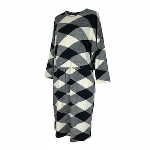 May include: A long-sleeved dress with a black, white, and gray diamond pattern. The dress has a round neckline, a cinched waist, and a knee-length hemline. The sleeves are three-quarter length.