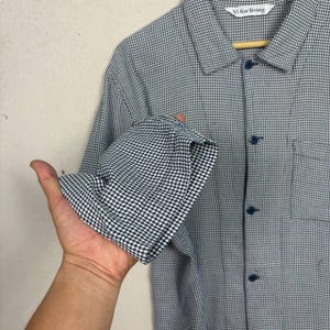 May include: A white ceramic mug with a black handle and the text "But First, Coffee" in a bold, black font. The mug is set against a blurred background, suggesting a cozy setting.