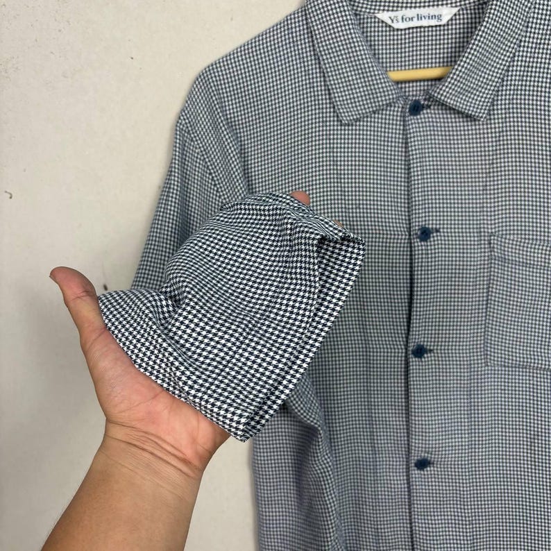 May include: A white ceramic mug with a black handle and the text "But First, Coffee" in a bold, black font. The mug is set against a blurred background, suggesting a cozy setting.