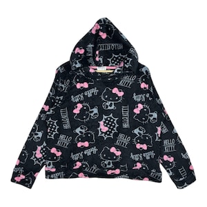 Puede incluir: Sudadera con capucha negra con un patrón repetido de personajes de Hello Kitty con lazos rosas y las palabras "Hello Kitty" en blanco. La sudadera tiene una capucha con cordón y mangas largas.