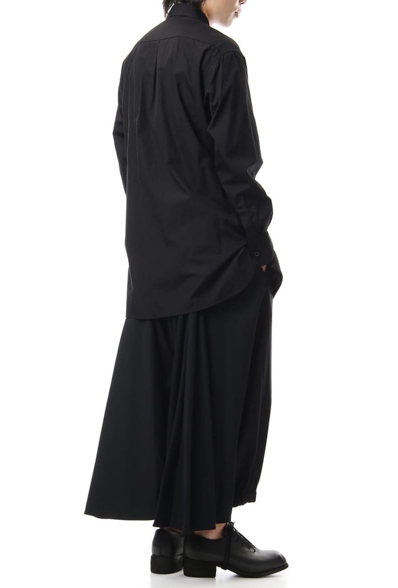 Op de afbeelding: Zwart ensemble bestaande uit een lange mouwen overhemd met knopen en een wijde broek. Het overhemd heeft een klassieke kraag en manchetten met knopen. De broek heeft een vloeiend, oversized ontwerp. De schoenen zijn van leer met een lage hak.