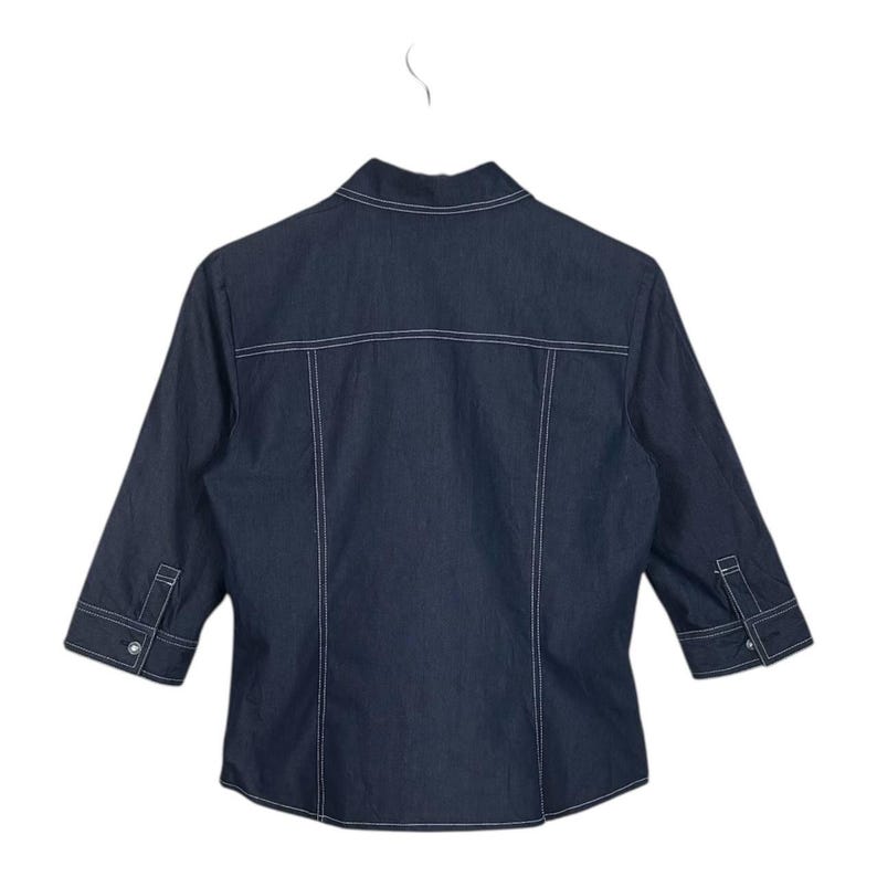 May include: Dark blue denim jacket with three-quarter sleeves, white stitching, and buttoned cuffs. The back of the jacket is visible, showcasing the tailored design and seams. A classic, casual outerwear piece.