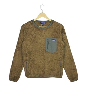 Könnte beinhalten: Ein brauner Fleece-Pullover mit grüner Tasche und Besatz. Das langärmlige Oberteil hat eine kleine Reißverschlusstasche auf der Brust und zwei Reißverschlusstaschen an der Taille. Das Markenlogo ist auf der Tasche sichtbar.