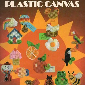 May include: A vintage craft book cover featuring a colourful illustration of 19 plastic canvas magnet designs. The designs include a rainbow, a house, a chicken, a ladybug, a bee, a frog, a gumball machine, an orange, an apple, a flower, a bird, and more. The book title is "Quick & Easy Magnets for Plastic Canvas" and the text "19 Designs by Anne Van Wagnen" is also included.