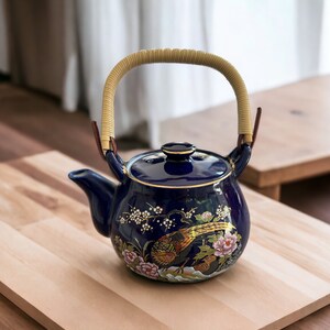 May include: A blue ceramic teapot with gold trim and a floral design. The teapot has a woven handle and a lid with a knob.