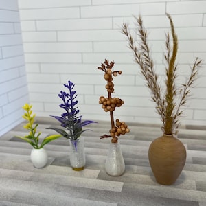 May include: Four small vases with different types of dried flowers. The vases are white, clear, and brown. The flowers are purple, yellow, and brown.
