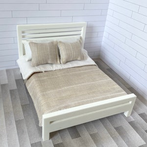 May include: White wooden bed frame with a beige striped blanket and two beige pillows with a subtle chevron pattern.