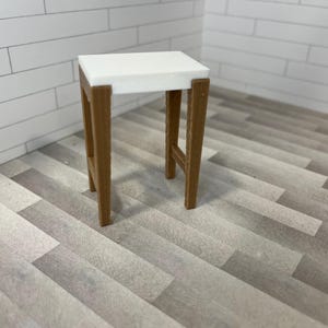 Puede incluir: Una mesa rectangular blanca con un marco de madera marrón. La mesa tiene un diseño simple con líneas rectas y una superficie plana.