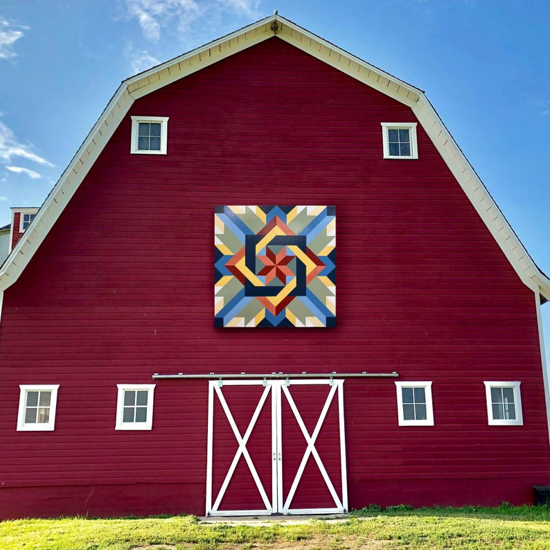 May include: A red barn with a white door and windows. The barn has a large painted design on the side, featuring a colorful geometric pattern.