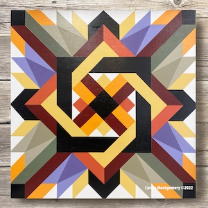 Könnte beinhalten: Geometrischer Quiltblock mit einem wirbelnden Muster in Gelb-, Orange-, Rot-, Braun-, Schwarz-, Grau- und Lilatönen. Der Quiltblock befindet sich auf weißem Hintergrund. "Carol Montgomery ©2022" steht in der rechten unteren Ecke.