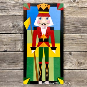 Peut inclure: Peinture géométrique colorée d'un soldat casse-noisette tenant un drapeau jaune. L'œuvre présente une veste rouge, des bottes noires et une couronne dorée sur un fond bleu et vert. Le nom et le copyright de l'artiste sont en bas.