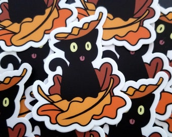 May include: A set of black cat stickers with orange and brown fall leaves. The cats are wearing the leaves as hats and have their tongues sticking out.