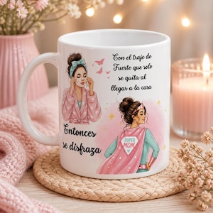 Könnte beinhalten: Weiße Keramik-Tasse mit Illustrationen und spanischem Text. Eine Illustration zeigt eine Frau in einem rosa Bademantel, die eine Gesichtsmaske aufträgt. Die andere zeigt eine Frau in einem Superhelden-Umhang. Der Text enthält "Super Mom".